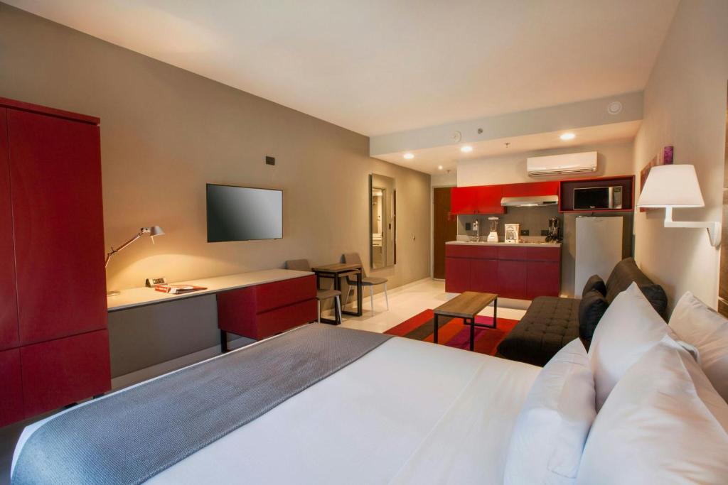 a hotel room with a large bed and a kitchen at City Express Plus by Marriott Cabo San Lucas in Cabo San Lucas