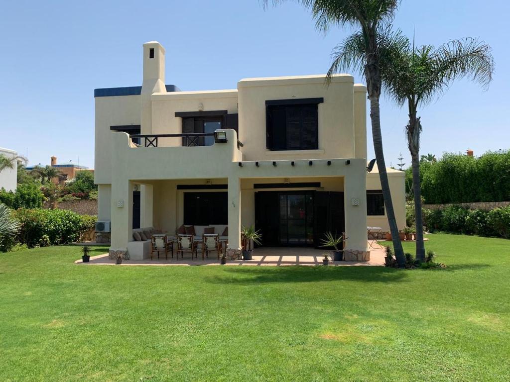 Mājid Abū ZaydにあるSerene Escape 4 Bedrooms Villa - Hacienda Redの芝生とヤシの木のある大きな白い家