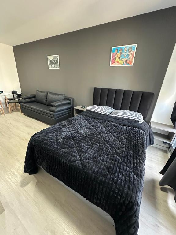 een slaapkamer met een zwart bed en een bank bij MOVISTAR ARENA PREMIUM Thames 56 4 piso 406 Cochera y Seguridad in Buenos Aires