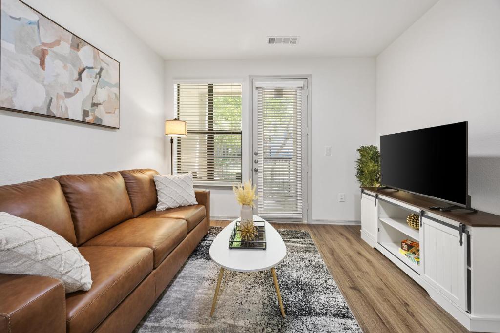 a living room with a brown couch and a flat screen tv at Brightshaven CoolSprings, Modern 1Bed with EV Parking in Frisco in Frisco