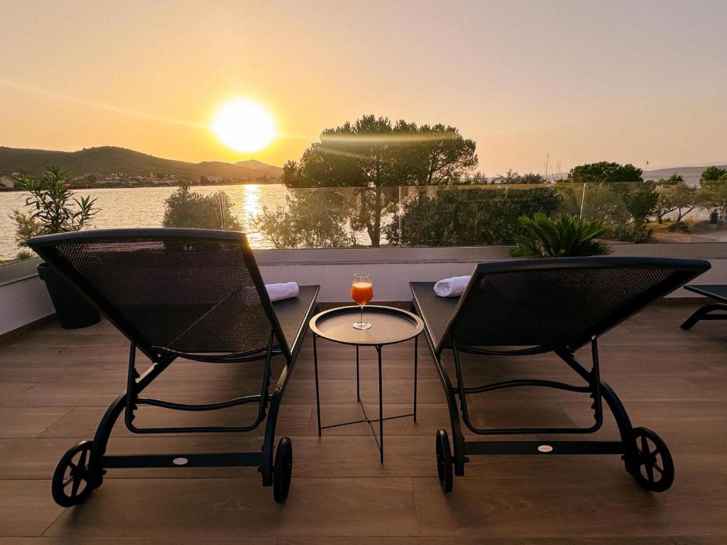 two chairs and a table on a balcony with the sunset at Beachfront house Miamore - 10 m from the sea in Pašman