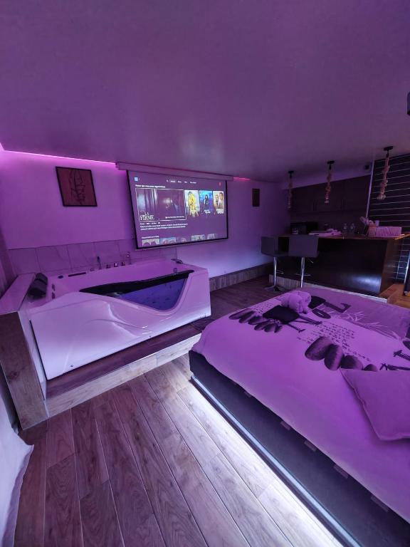 a purple bedroom with two beds and a tv at L'escale du Donon - Chambre Blanche in Grandfontaine