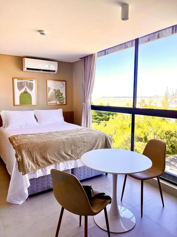 a bedroom with a bed and a table and a large window at SH Flat in João Pessoa