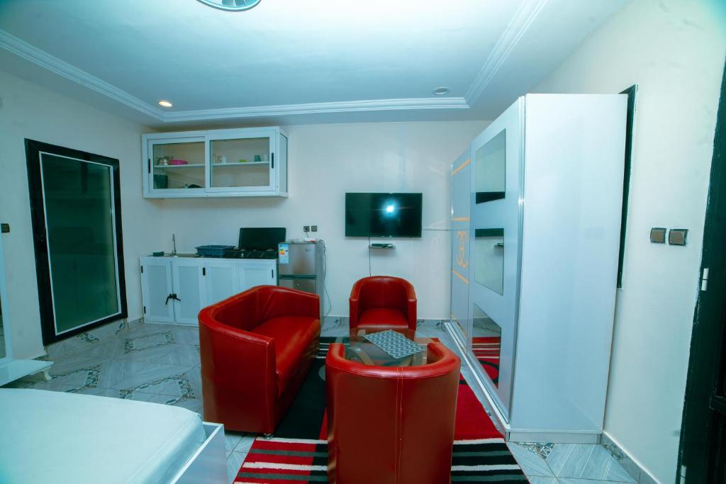 a living room with red chairs and a tv at Residence Cabral in Guediawaye