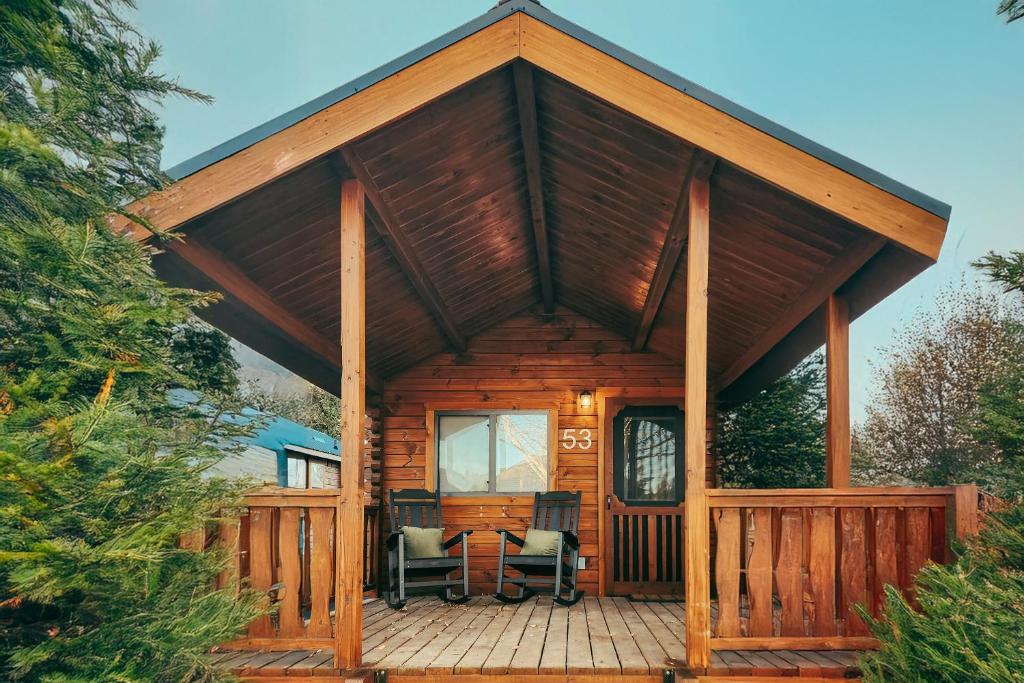 una cabina con un grande portico in legno con due sedie di Blue Buffalo Resort a Island Park