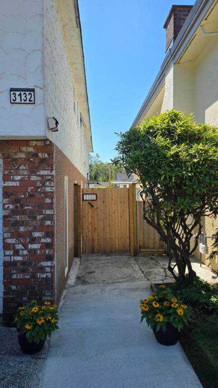 a building with a gate and a tree next to a sidewalk at Maplewood Hostel in Vancouver