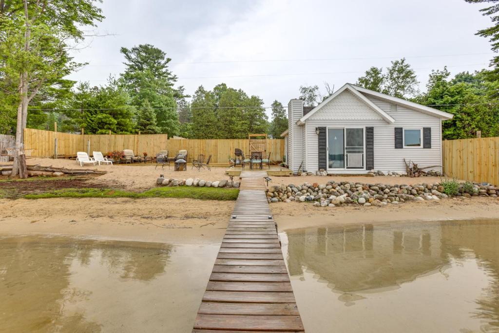 a wooden walkway over the water in front of a house at Beach Access and Dock Little Traverse Lake Cottage! in Maple City