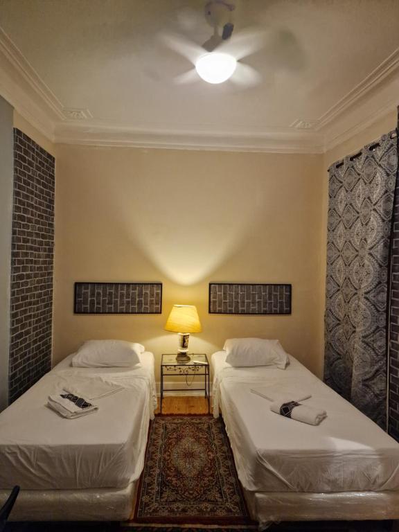 two beds in a room with a ceiling fan at D I N Hospedagem lisboa in Lisbon