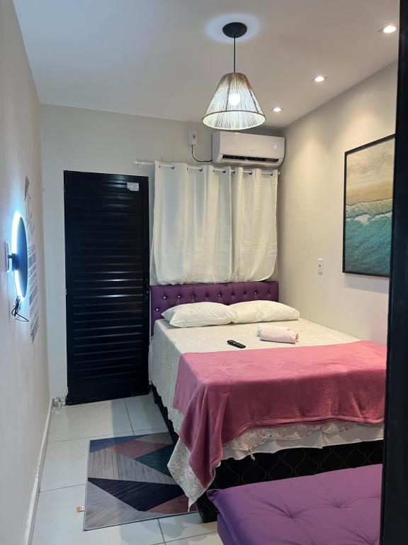 a bedroom with a bed with a pink blanket at Casa Lilás Pipa A 4 min da praia e perto de tudo in Pipa