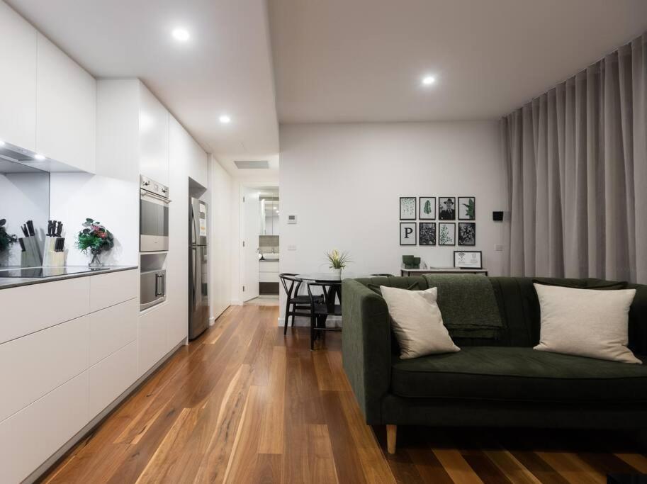 a living room with a green couch and a kitchen at The Chifley by Parbery Property Group in Campbell