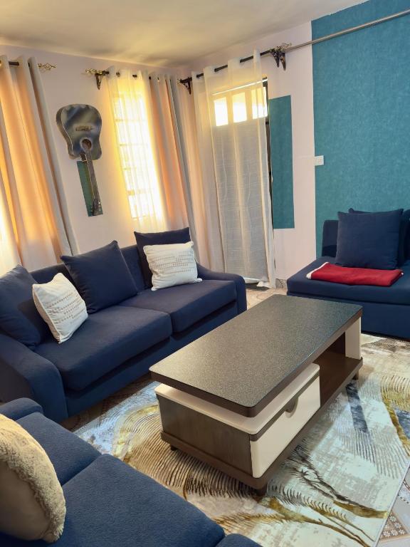a living room with a blue couch and a coffee table at Toly’s Spacious One Bedroom in Nairobi