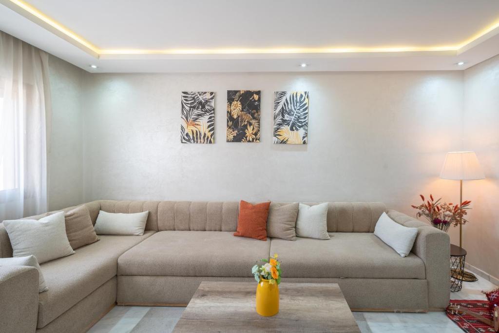 a living room with a couch and three paintings on the wall at LUXURY APARTMENT IN THE HEART OF MARRAKECH GUELIZ in Marrakech