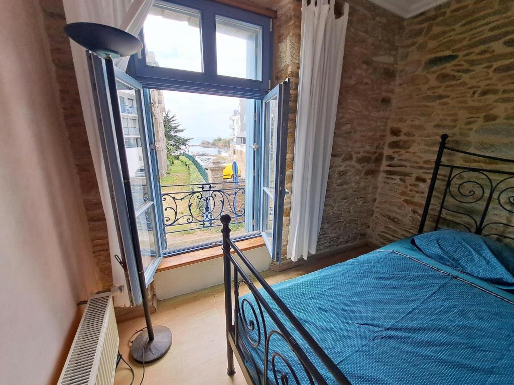 une chambre avec un lit et une grande fenêtre dans l'établissement First floor studio near the beach, au Pouldu