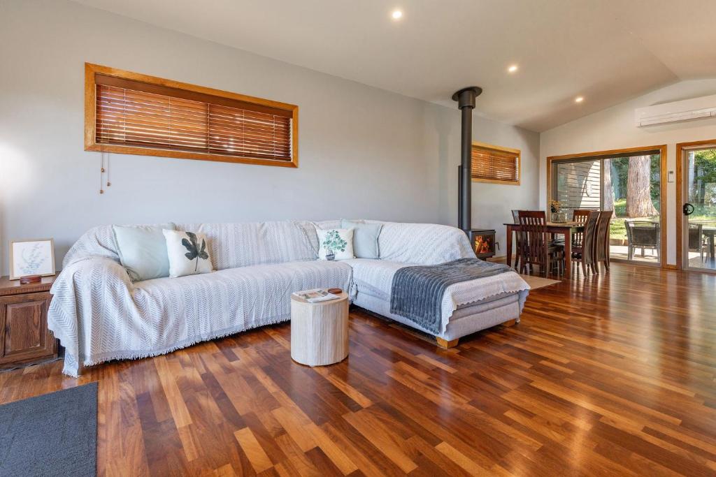 a living room with a couch and a wooden floor at Follow The Sun in Smiths Lake