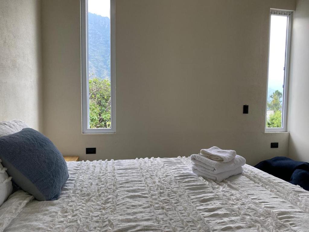 1 Schlafzimmer mit einem weißen Bett und 2 Fenstern in der Unterkunft Hiking San Juan in Cataltzul