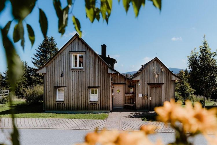 une grande maison en bois avec un garage dans l'établissement Ferienhäuser im Torfhaus Harzresort, Torfhaus, à Torfhaus