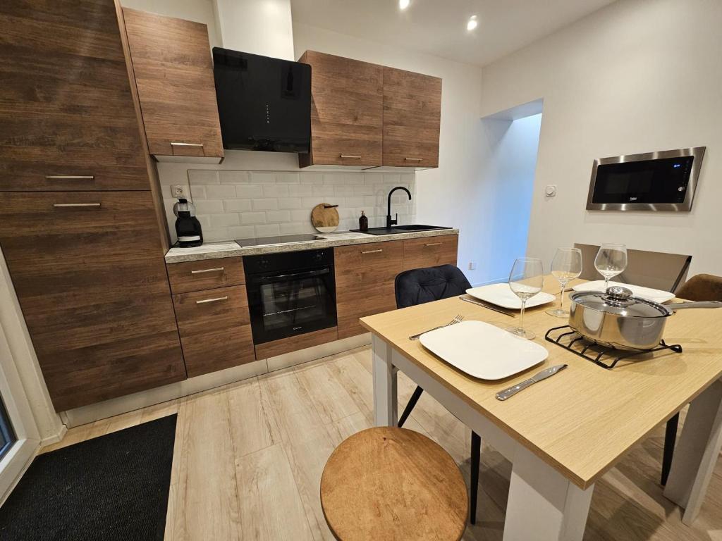 a kitchen with wooden cabinets and a table with wine glasses at Maison de ville rénovée avec garage privatif à Épinal - FR-1-589-834 in Épinal