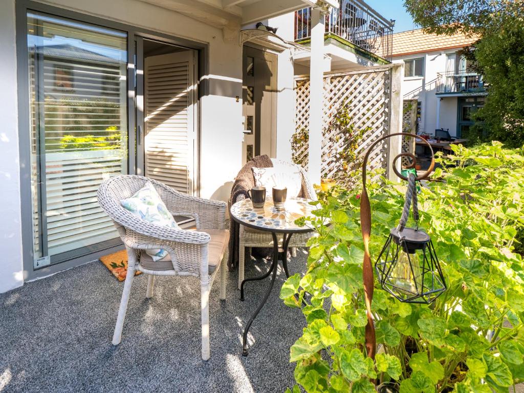 a patio with a table and chairs and a plant at Akaroa Hideaway - Cosy Studio walk to Village - Studio 6 in Akaroa