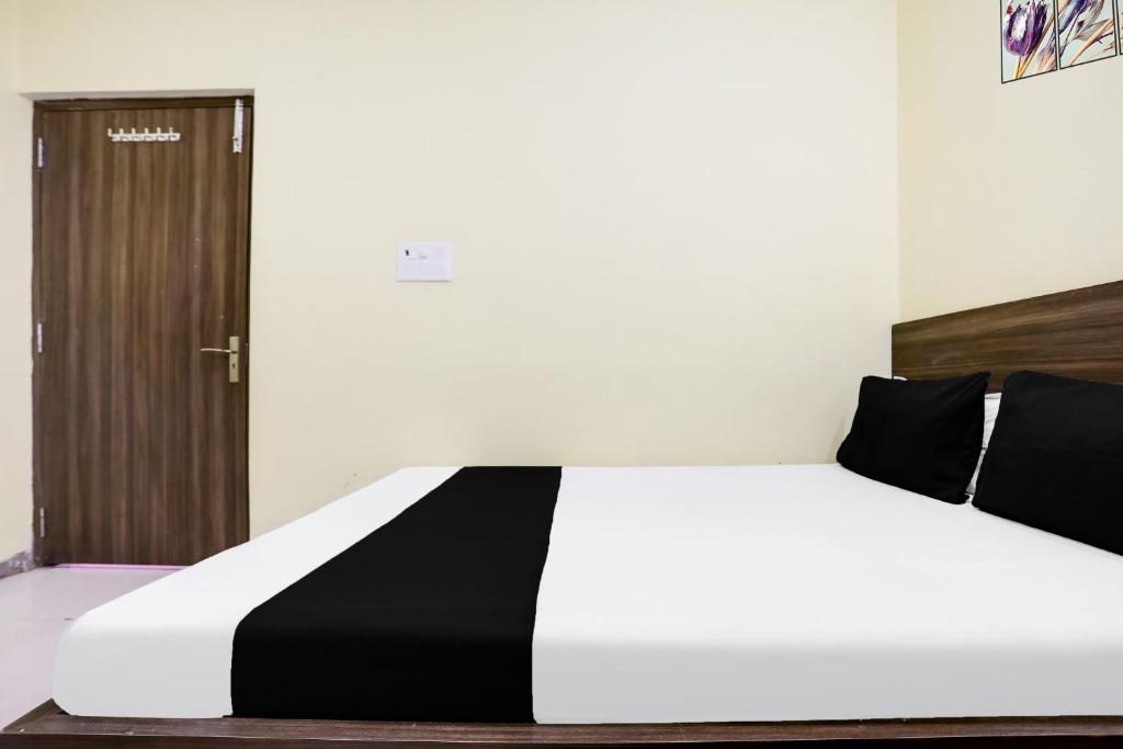 a white and black bed in a room with a door at Hotel O Divisha palace in Gaya