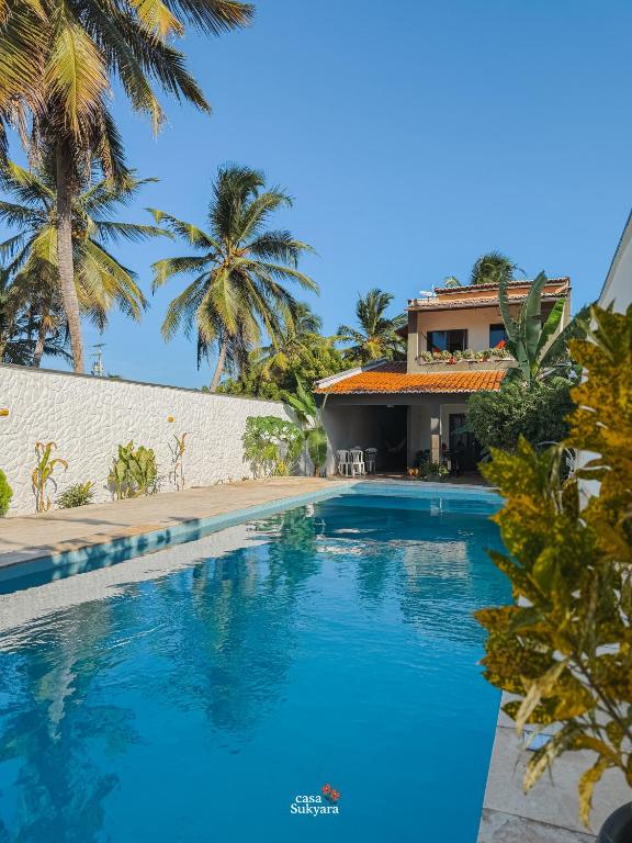 a swimming pool in front of a house with palm trees at Casasukyara in Amontada
