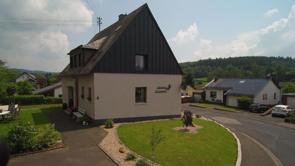 a white house with a black roof on a street at Gästehaus Eifelzauber in Kelberg