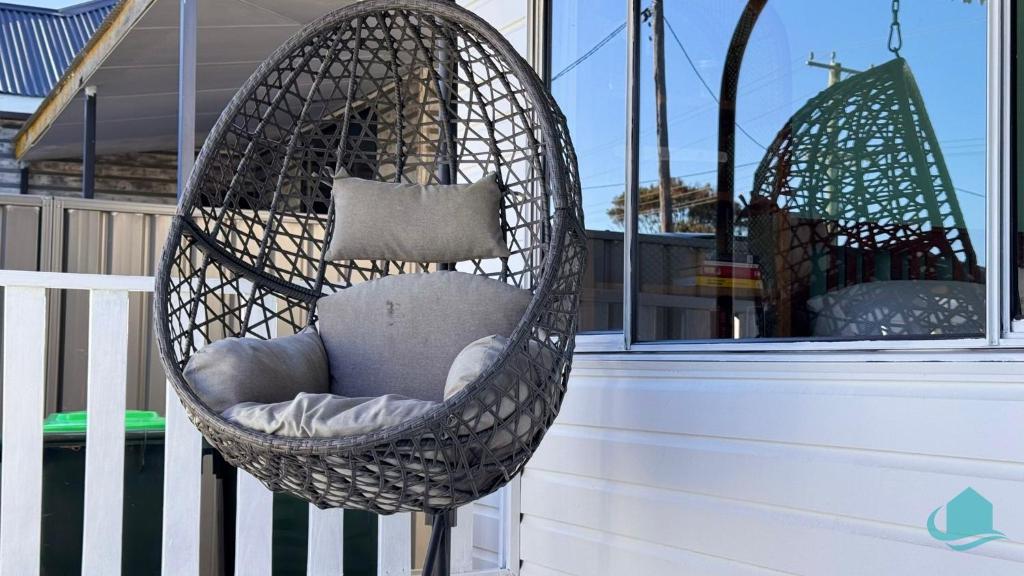 a hanging chair with a pillow on a porch at Barefoot at Blacksmiths Beach in Blacksmiths