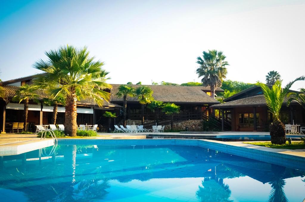 una piscina frente a una casa con palmeras en Canto da Floresta Ecoresort en Amparo