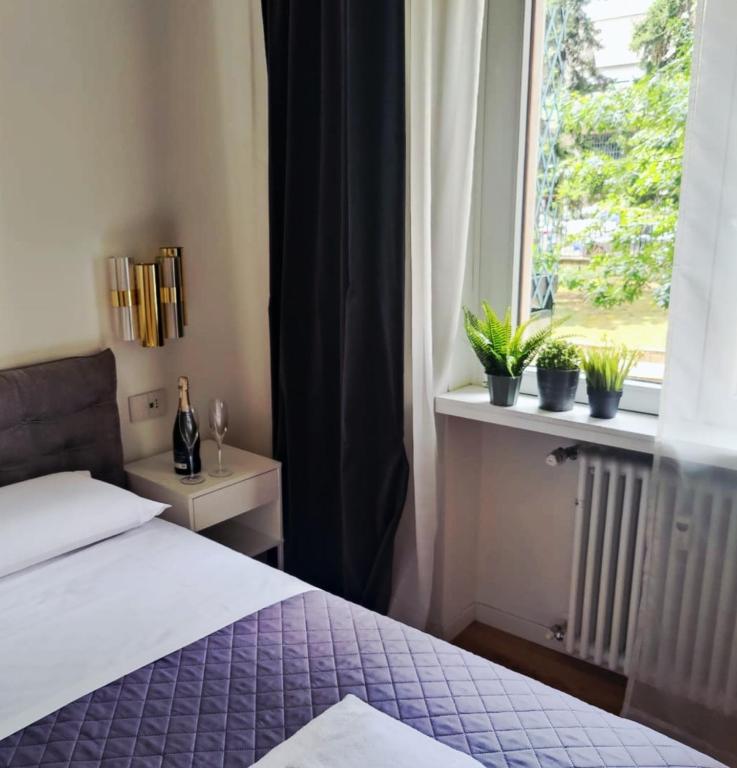 a bedroom with a bed and a window with potted plants at Cozy Apartment between Sempione, City Life and MiCo ! in Milan