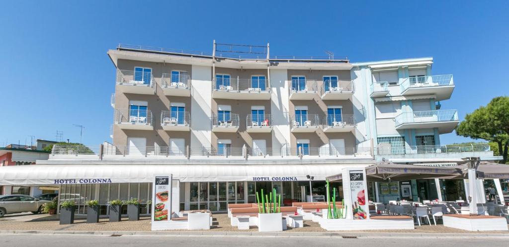 a large white building with tables and chairs in front of it at Hotel Colonna in Lido di Jesolo