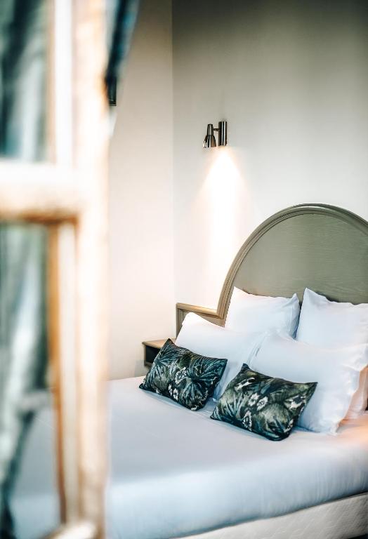 a bed with pillows on it in a room at Hôtel La Tour des Anglais in Mayenne