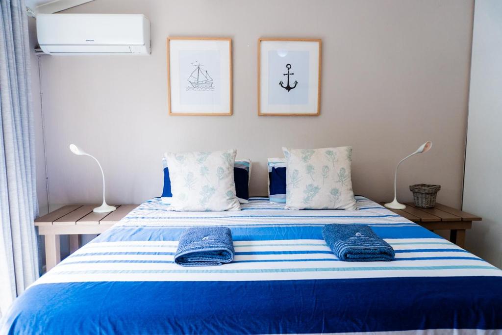 a bedroom with a blue and white bed with two pillows at The Wooden Anchor spacious and modern in Zinkwazi Beach