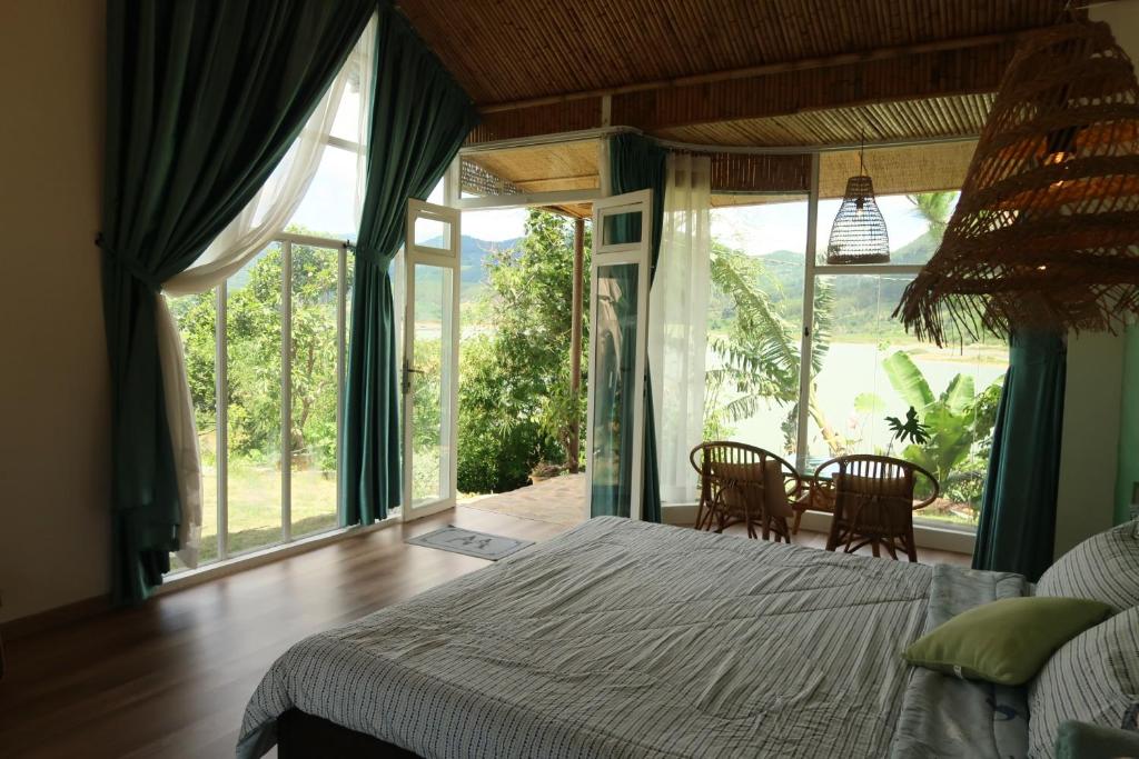 a bedroom with a bed and a table and chairs at Rosee de Kala - Golden Buurin in Di Linh