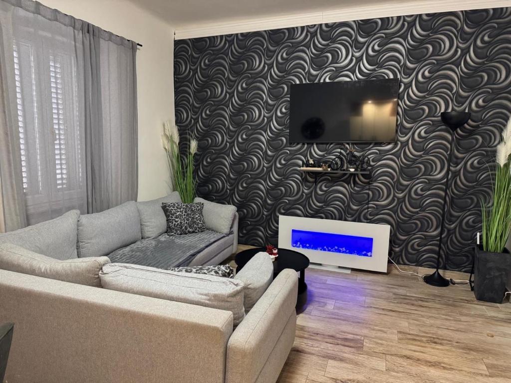 Apartment Lorena -prizemlje,EG,pianterreno في رييكا: غرفة معيشة مع أريكة وتلفزيون على الحائط