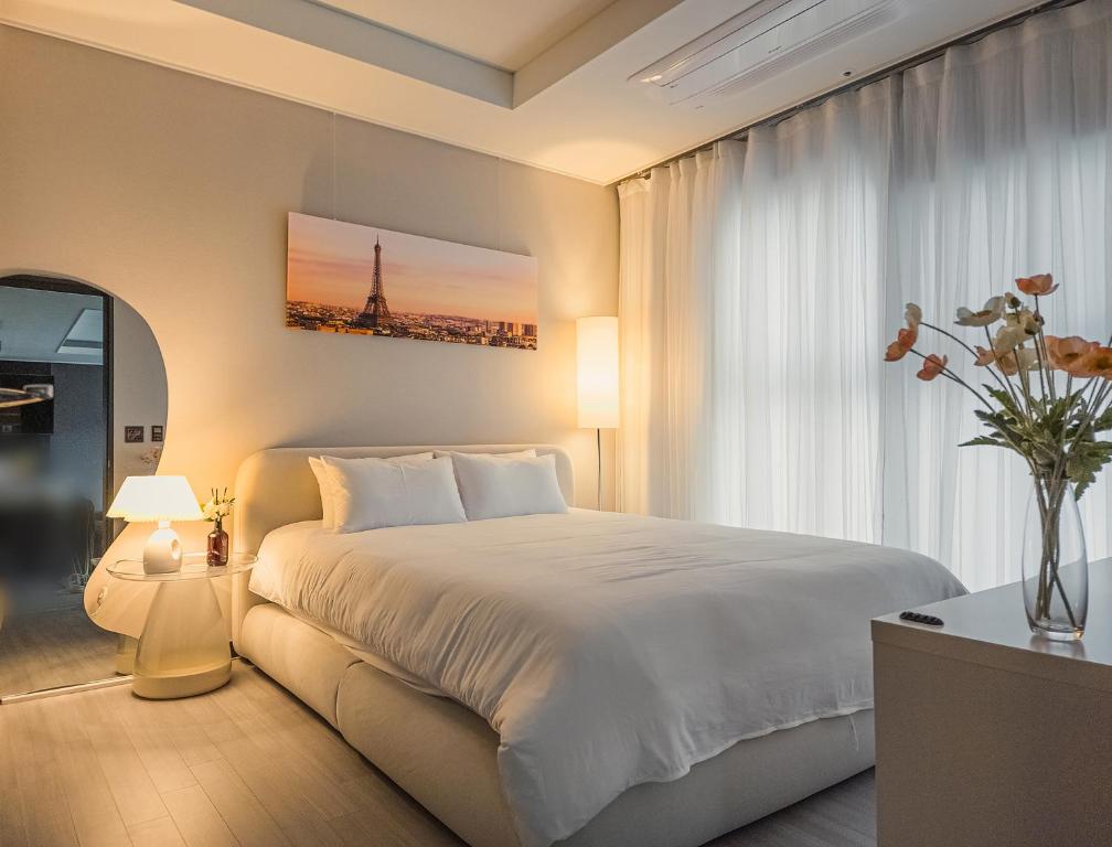 a bedroom with a large white bed and a window at Vourne Osiria in Busan