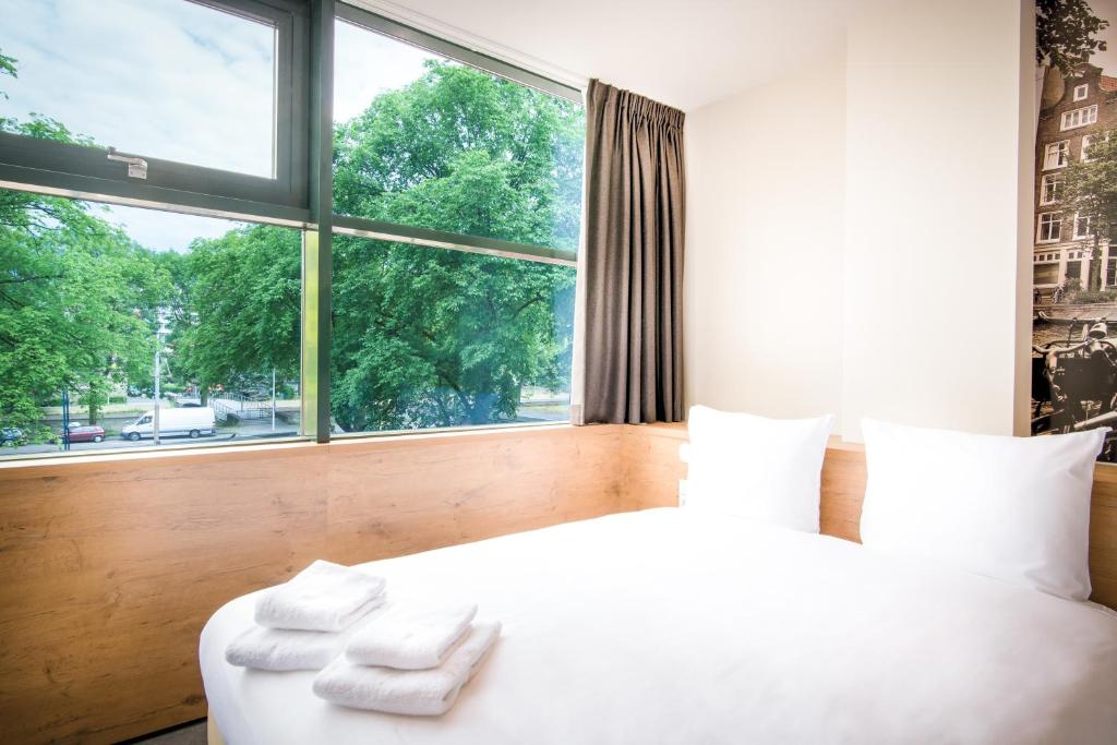 a bedroom with a white bed and a large window at Citiez Hotel Amsterdam in Amsterdam
