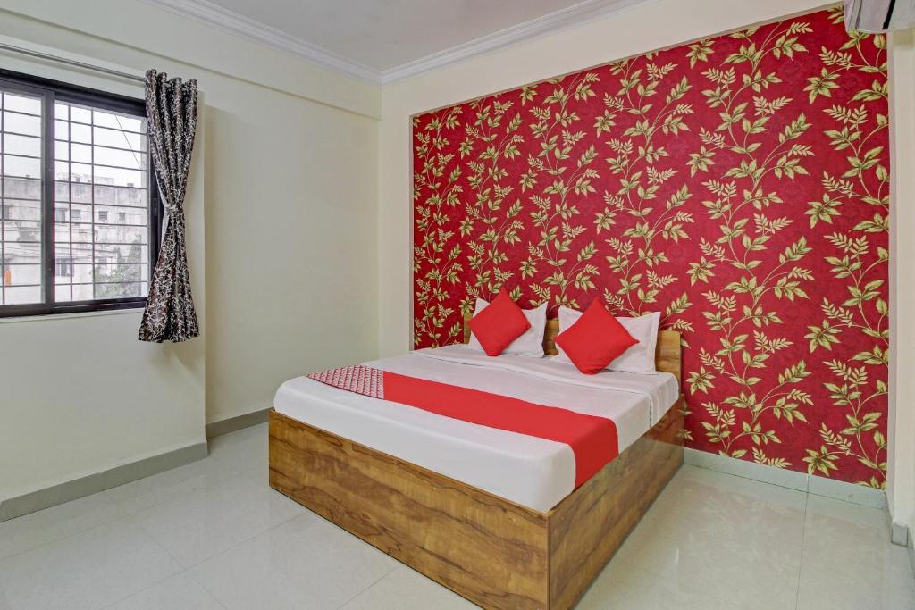 a bedroom with a bed with a red wall at Hotel O Sai Executive Lodging in Māngvādi