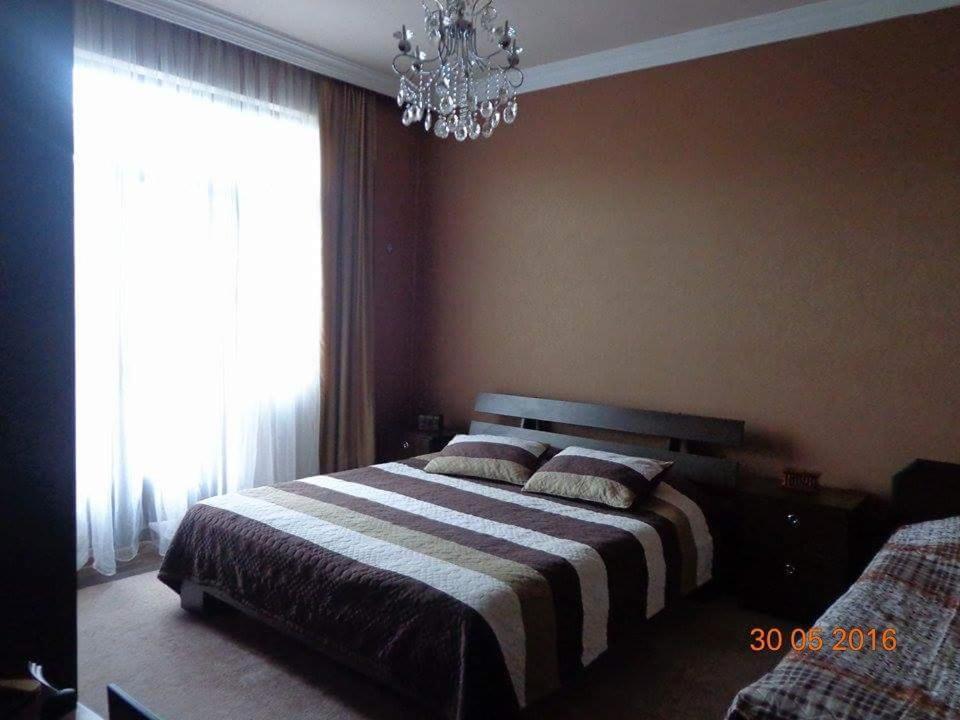 um quarto com uma cama com um lustre e uma janela em Kobuleti em Kobuleti