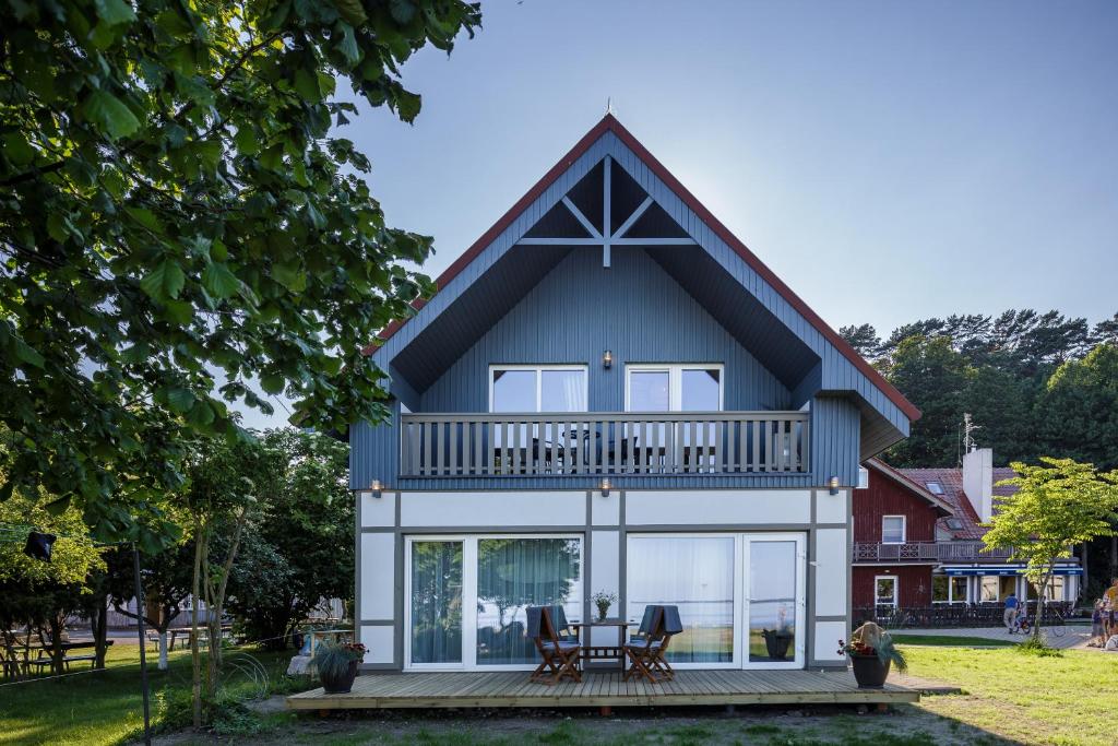 a house with a gambrel roof and a deck at Vila Stinta in Juodkrantė