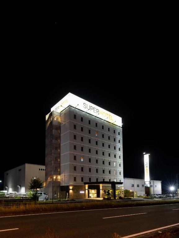 四国中央市Super Hotel Shikoku-chuo的晚上，建筑物顶部有标志