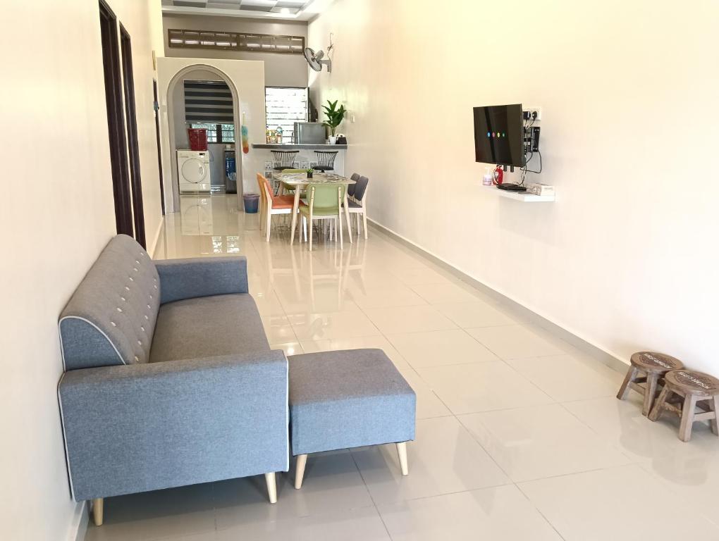 a living room with a blue couch and a table at Azzahra Homestay in Permatang Pauh