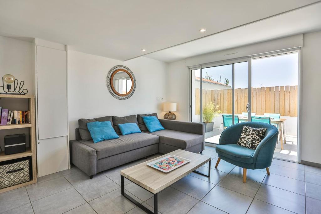 a living room with a couch and a chair at La tranquilité bleue - Maison avec Parking cloturé in Les Sables-dʼOlonne