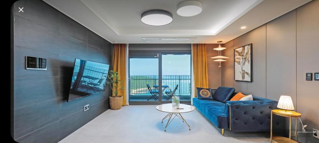 a living room with a blue couch and a balcony at 오시리아 해운대 in Busan