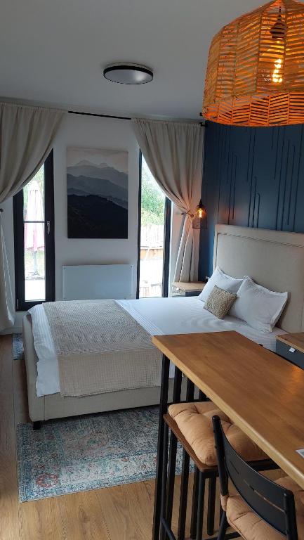 a bedroom with a bed and a wooden table and a dining room at Căsuța de oaspeți in Ghermăneşti