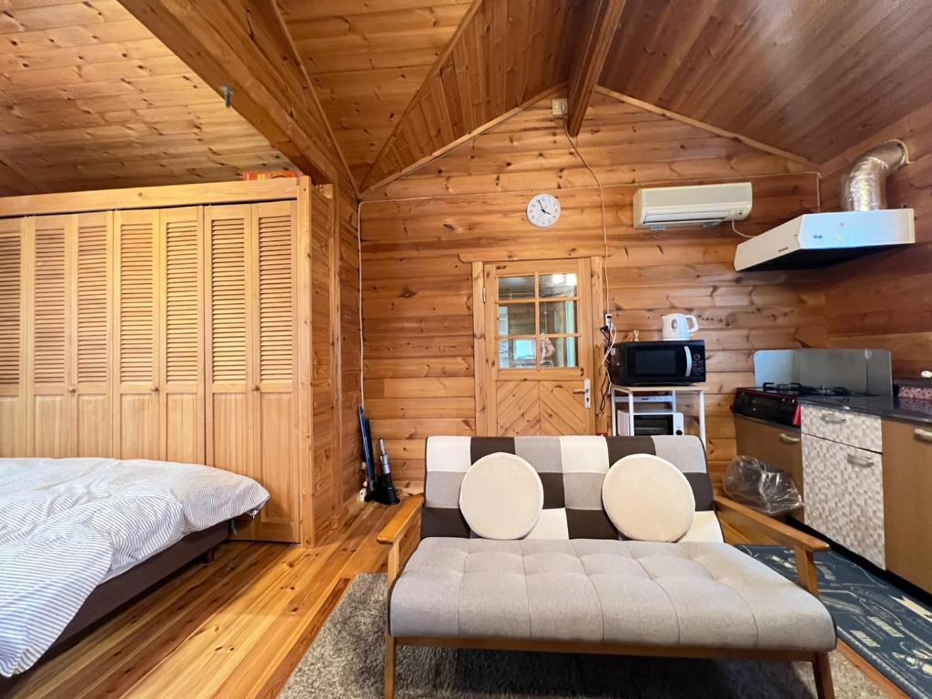 ein Schlafzimmer mit einem Bett und einer Couch in einem Zimmer in der Unterkunft コテージコッタロ in Gojikkoku