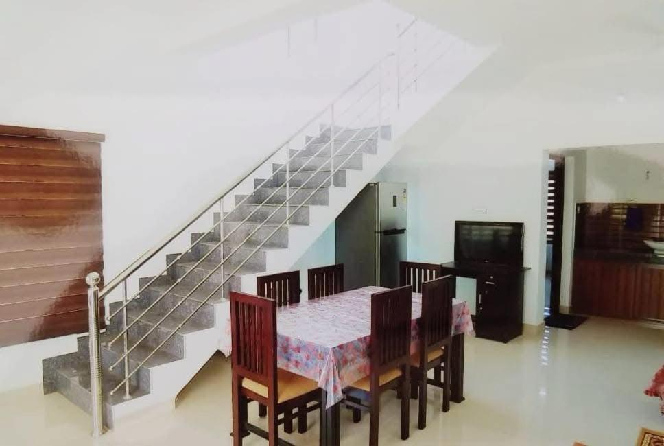 Un comedor con mesa y sillas y una escalera. en Seawind, en Kannur