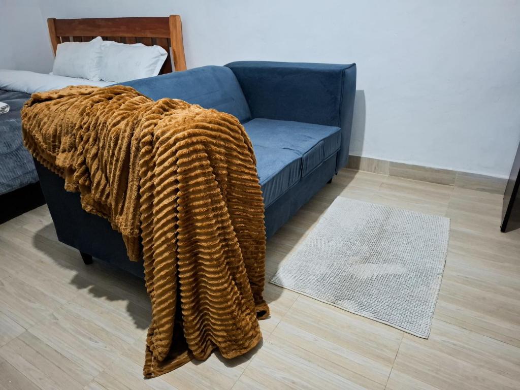 a blanket on a couch in a living room at Maasai Boma Place - Studio Apartment in Juja
