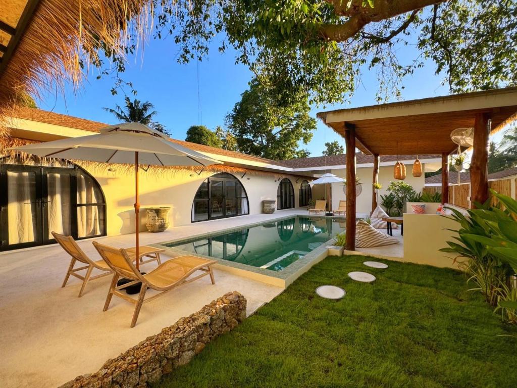 un patio trasero con piscina, una silla y una sombrilla en Boho Village, en Ko Pha Ngan