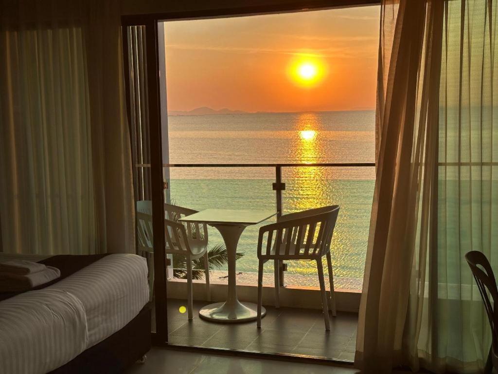 a room with a view of the ocean with a table and chairs at Golden Dragon Beach Resort Pattaya (Bang Lamung) in Ban Rong Po
