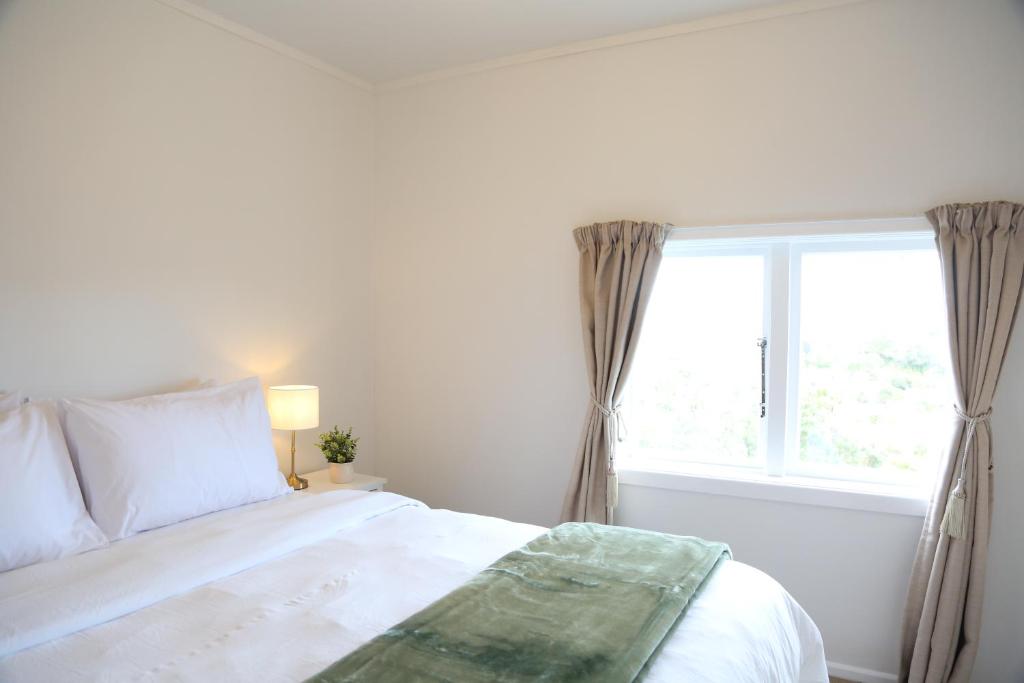 Una habitación blanca con una cama y una ventana en Skyline Urban - Entire Apartment with View, Parking, Netflix, and Nespresso, en Wellington