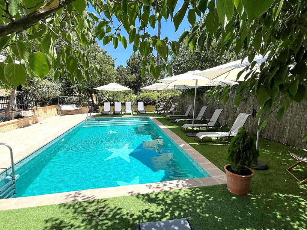 ロンダにあるXXV- Finca La Cantara - La Cantara Amarillaの庭園内のスイミングプール(椅子、パラソル付)
